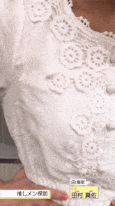 a close up of a woman 's white lace top with a yellow label that says " 田村 真佑 "