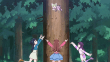 a group of girls are standing around a tree with a cat on it