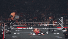 a wrestler with the letter b on his shorts is fighting another wrestler in a wrestling ring
