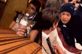 a woman is sitting at a table holding a bottle of water next to a boy .