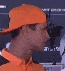 a man wearing an orange hat and an orange shirt is looking at another man .