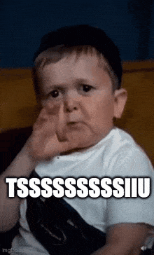 a little boy is sitting on a couch covering his nose with his hand .