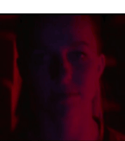 a close up of a person 's face in a dark room with a red light behind them .