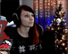 a woman wearing headphones is sitting in front of a christmas tree in a room .