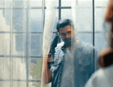 a man is standing in front of a window holding an umbrella and looking out the window