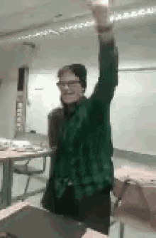 a woman in a green shirt is raising her arm in the air