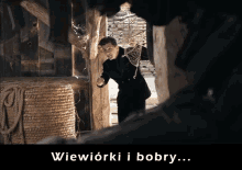 a man in a black suit is standing in a dark room with the words wiewiorki i bobby written below him