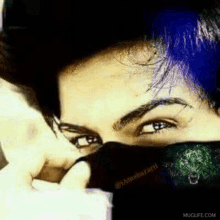 a close up of a person covering their face with a black scarf