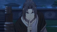 a man with a ponytail has his finger on his mouth