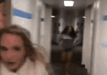 a woman is walking down a hallway with a man behind her .