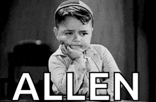 a black and white photo of a little boy sitting at a table with his hand on his chin and the word allen above him .