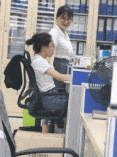 a woman sits at a desk in front of a sign that says ' hong kong '