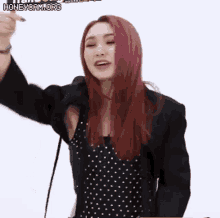 a woman with red hair is wearing a black jacket and a black polka dot dress .