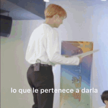 a man in a white shirt and black pants is standing in front of a sign that says lo que le pertenece