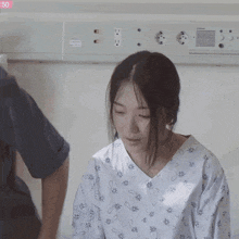 a woman in a hospital gown with a floral pattern