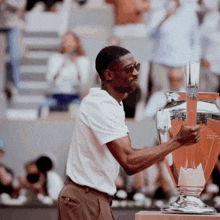 a man in sunglasses holds a trophy in his hand