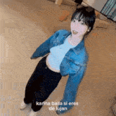 a woman in a denim jacket and a crop top is dancing .