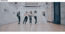 a group of women are dancing in front of a wall that says wne on it