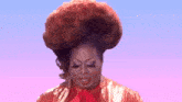 a drag queen is wearing a large red wig and a red bow tie .