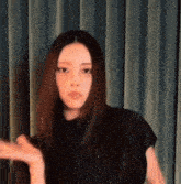a woman with long hair is standing in front of a curtain and making a funny face .