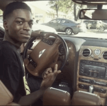 a man is sitting in a bentley car and giving a peace sign