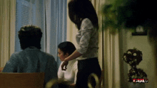 a woman is standing in front of a man and a woman in a room that says full on the bottom right