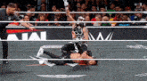 a man in a mask is wrestling another man in a ring with a w logo on the ropes