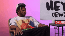 a man sits in front of a sign that says hey