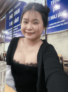 a woman is smiling in front of a blue sign that says " e mai ia "
