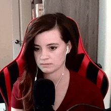a woman wearing headphones and a red shirt is sitting in a red chair .