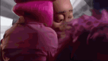 a close up of a person 's face with pink hair and a purple background .