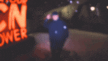 a blurry picture of a man standing in front of a neon sign that says " n "