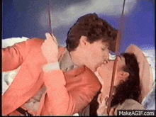 a man and a woman are kissing on a bed in a room .