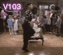 a woman is dancing in a room with balloons and a sign that says v103