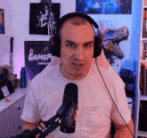 a man wearing headphones stands in front of a microphone in front of a sign that says gamer