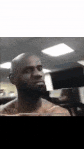 a bald man with a beard is lifting a dumbbell in a gym
