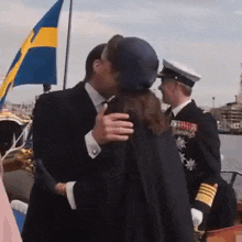 a man in a suit and tie is kissing a woman in front of a swedish flag .