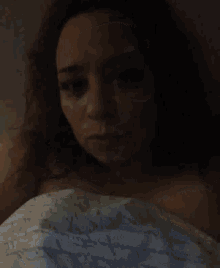 a woman with curly hair is laying in bed with a blanket on her shoulders .
