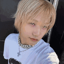a person with blonde hair is wearing a white shirt and a silver necklace