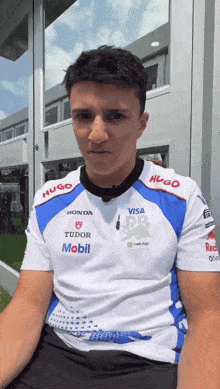 a man wearing a shirt with honda tudor and mobil logos on it