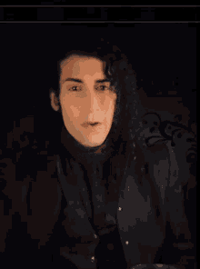a man in a black jacket holds a glass in his hand