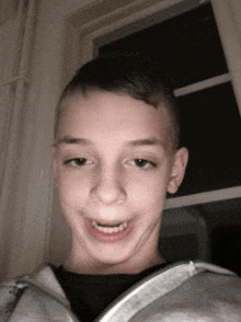 a young boy is making a funny face while wearing a hoodie