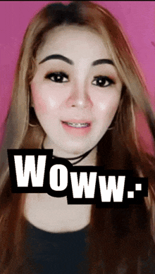 a woman with braces on her teeth stands in front of a sign that says woww