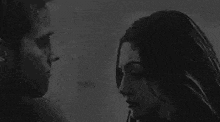 a man and a woman are looking at each other and kissing in a black and white photo .