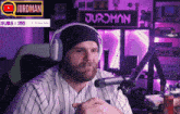 a man wearing headphones is sitting in front of a sign that says jurdman subs 155