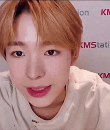 a close up of a young man 's face with a white shirt on and pink lips .