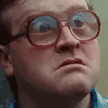 a man wearing glasses and a blue shirt is making a funny face .