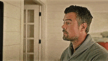 a man with a beard is wearing a robe and looking at a television .