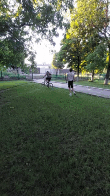 a person riding a bike in a park while another person walks