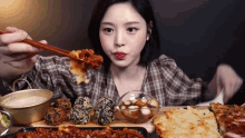 a woman is eating food with chopsticks while sitting at a table with plates of food .